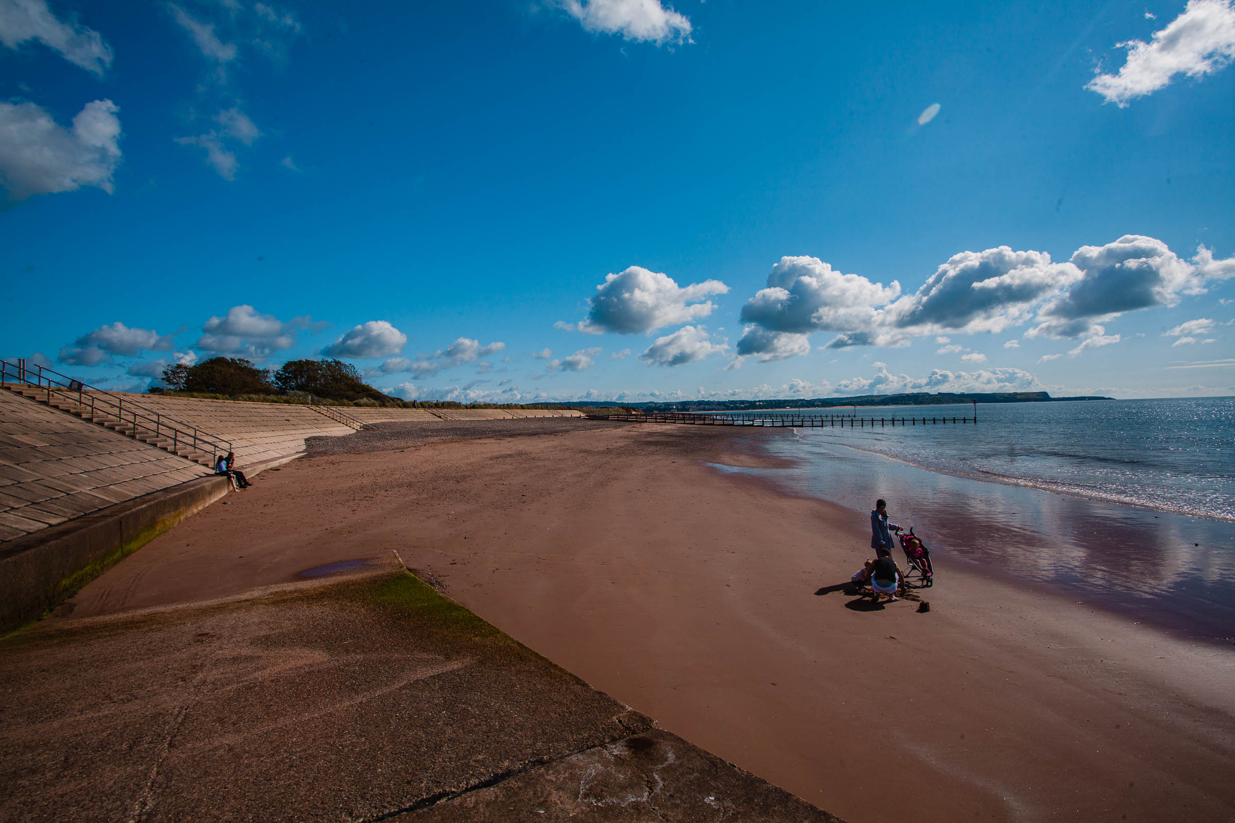 Familly with pushchair on the beech